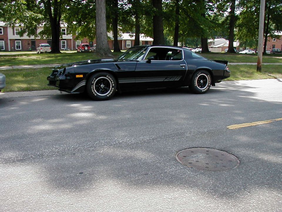 Black Z28 coupe parked on asphalt, side view. Cooper Cobra tires visible