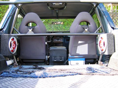 1985 Ford Bronco - Modified 1985 Ford Bronco interior with racing seats, roll cage, and aftermarket audio equipment.