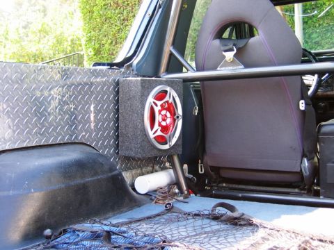 1985 Ford Bronco - The interior of an SUV shows a custom speaker installation and racing seat, suggesting off-road modifications.