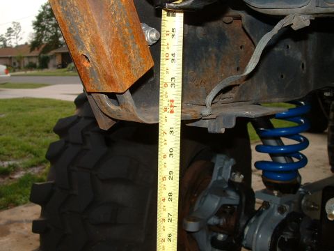1995 Ford Bronco - A measuring tape is used to assess the height of the suspension system on a vehicle's tire.