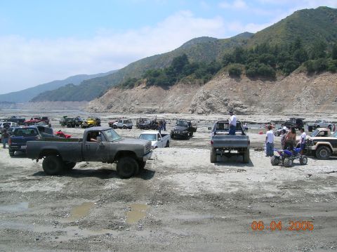 1985 Ford Bronco - A group of off-road vehicles gather in a dry, mountainous area on a sunny day.