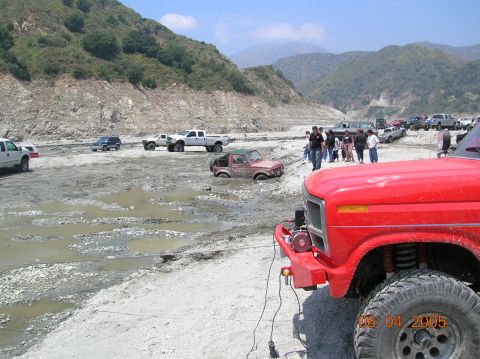 1985 Ford Bronco - Off-road vehicles navigate a challenging, muddy terrain with steep, rocky hillsides.