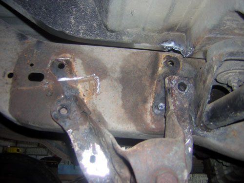 Rusted frame section with visible welds and mounting brackets