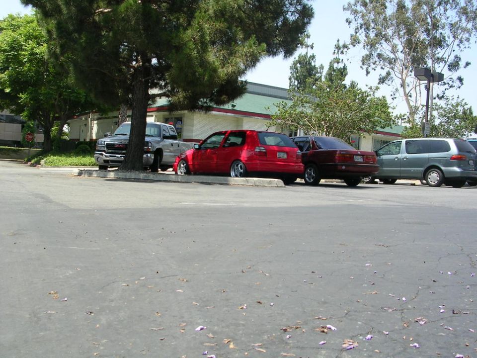 red hatchback parked next to a maroon sedan and a silver minivan
