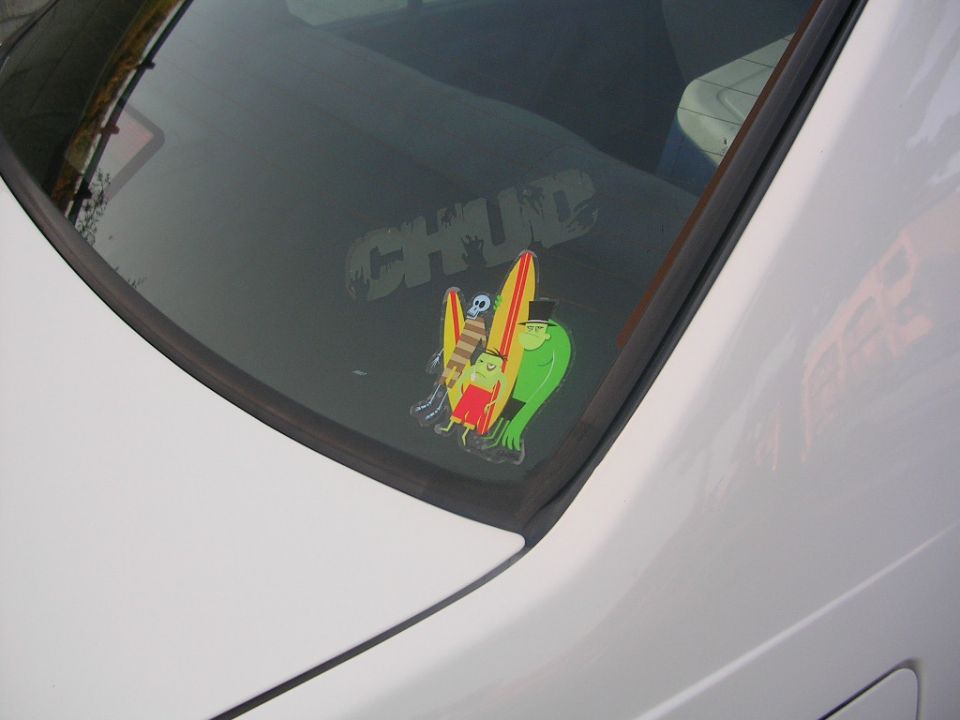 Rear window with CHUD sticker and cartoon characters with surfboards