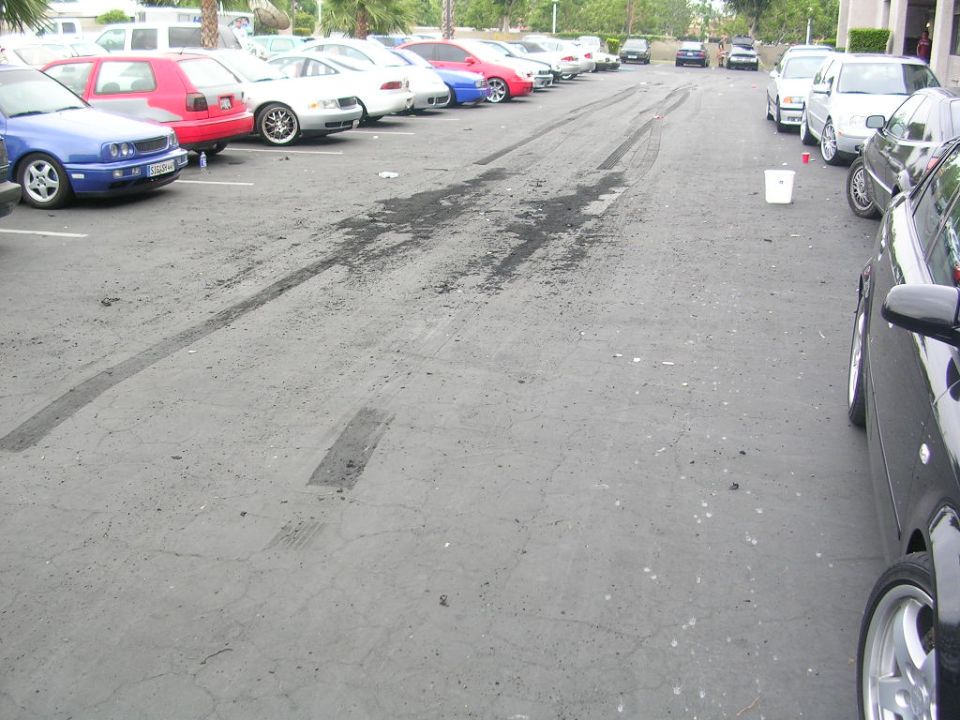 Parking lot with tire marks and several cars parked in rows