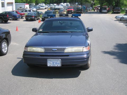 1991 Ford LTD Crown Victoria - A dark blue police car is parked in a lot with other vehicles visible in the background.