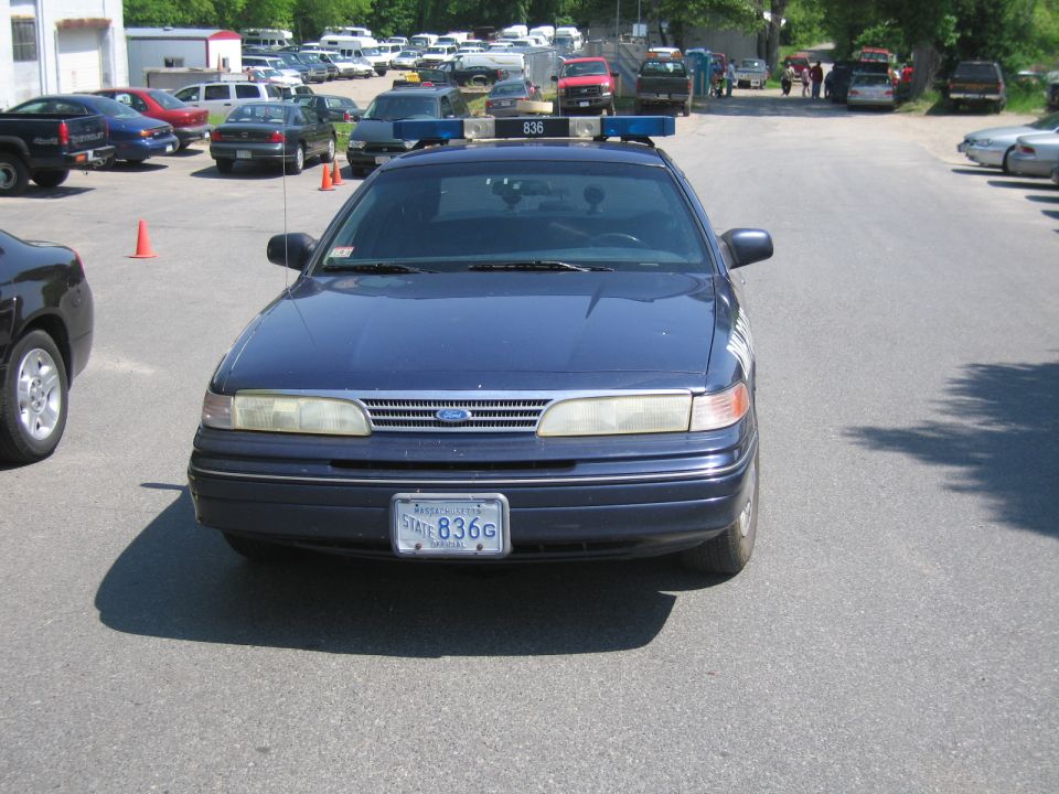 Front view of a 1991 Ford Crown Victoria LTD police car with a light bar on top and license plate 836G