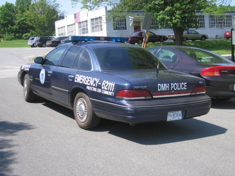 1991 Ford LTD Crown Victoria - A blue police car with emergency markings is parked on asphalt, with another car visible behind it.
