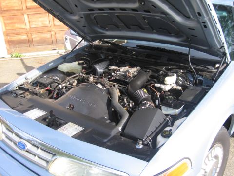 1991 Ford LTD Crown Victoria - The engine bay of a 1991 Ford Crown Victoria LTD, showing the engine and surrounding components with the hood raised.