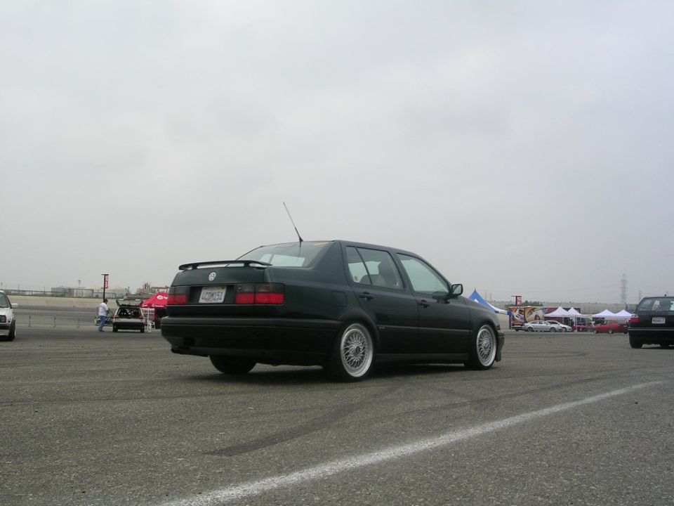 Dark green sedan with a spoiler, seen from the rear quarter