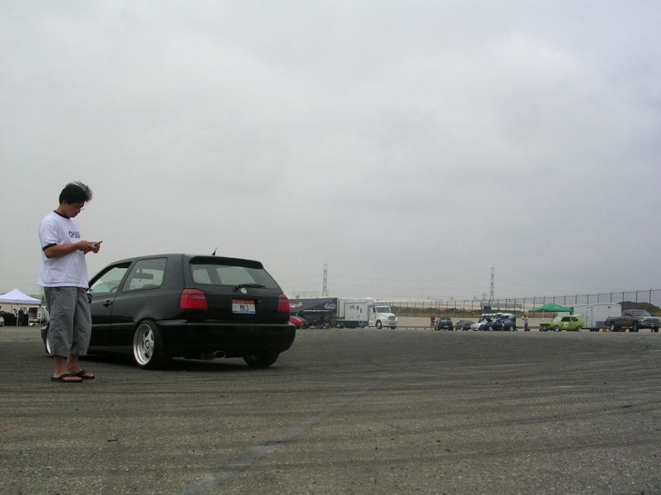 Black Volkswagen Golf GTI parked on asphalt, person looking at phone