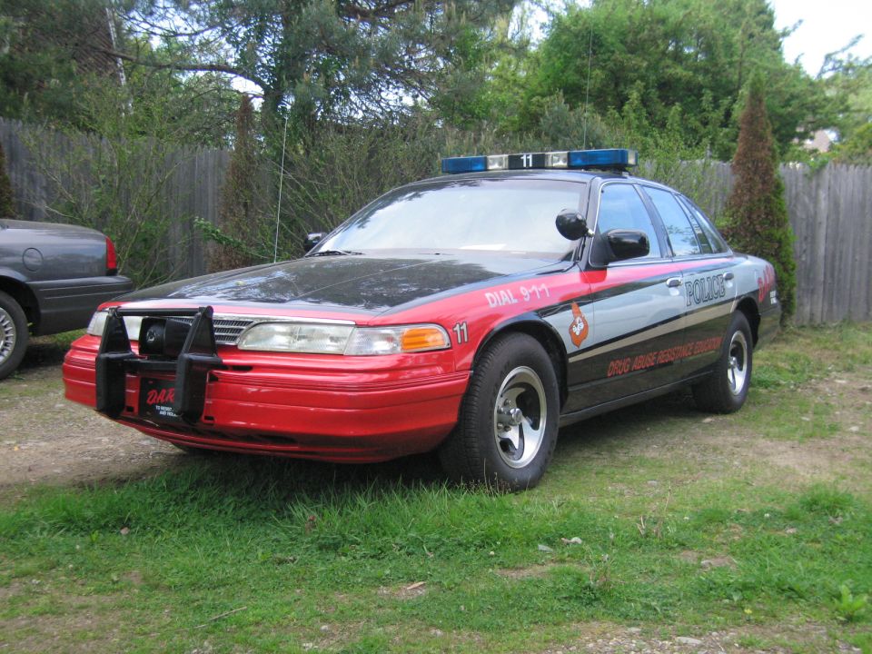 Red and black police car with "POLICE" text and "DIAL 911" on the side