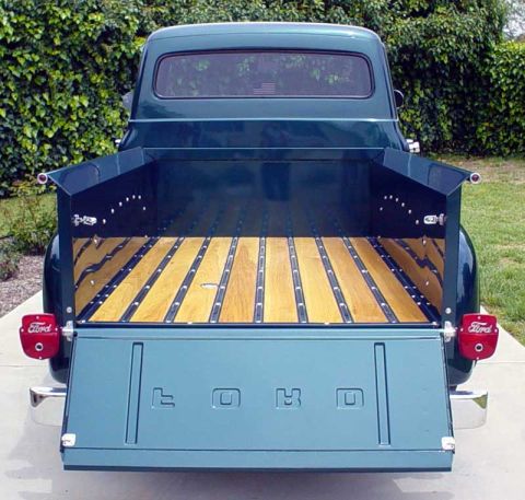 1956 Ford F-100 - Rear view of a 1956 Ford F-100 pickup truck, its restored wooden bed and tailgate with embossed Ford lettering.