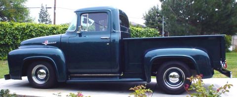 1956 Ford F-100 - Side profile of a dark green 1956 Ford F-100 pickup truck parked outdoors.