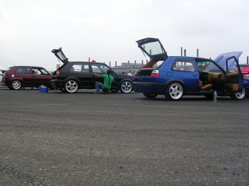 Three Volkswagen Golfs parked side-by-side, one blue, one black, one red