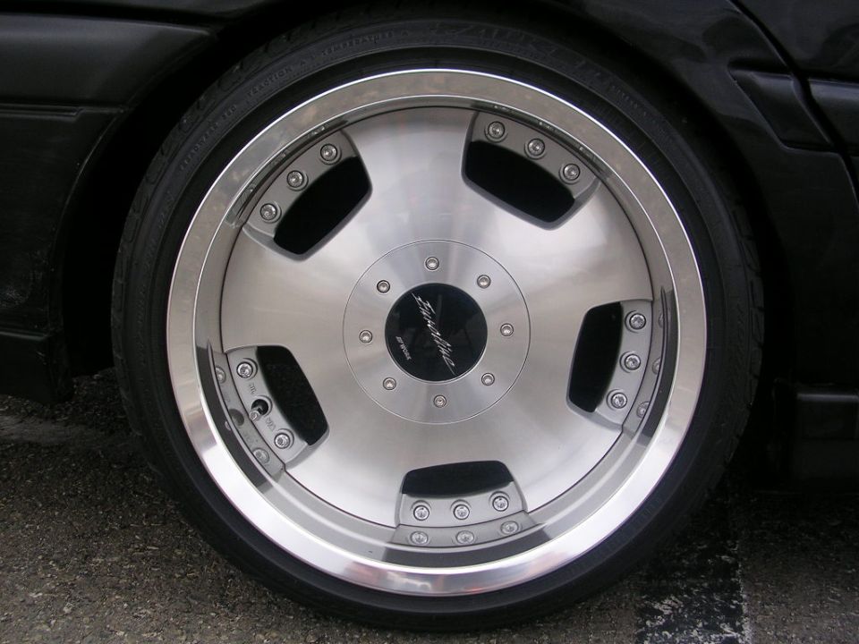 Chrome and silver five-spoke aftermarket wheel on a black car