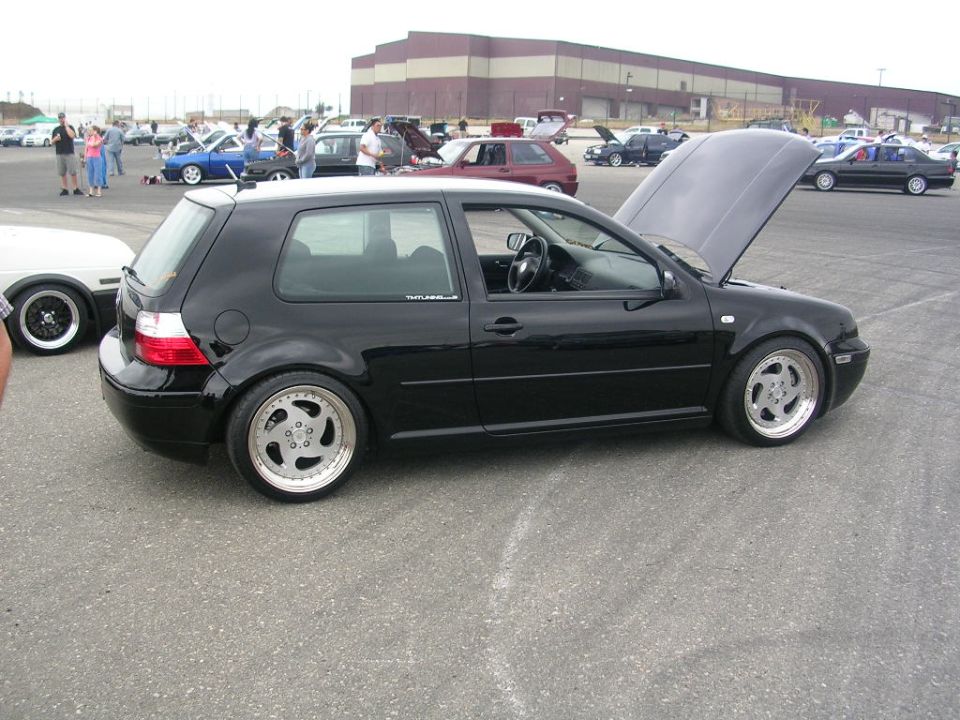 Black Volkswagen Golf GTI with hood open, parked at an outdoor car show