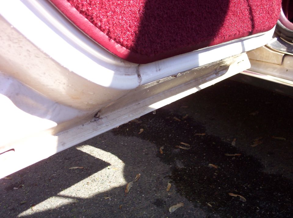 Close-up of a car's interior door sill with red carpet visible above