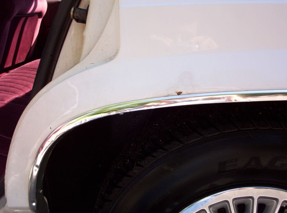 Close-up of a car's rear wheel well and part of the interior with red striped seats