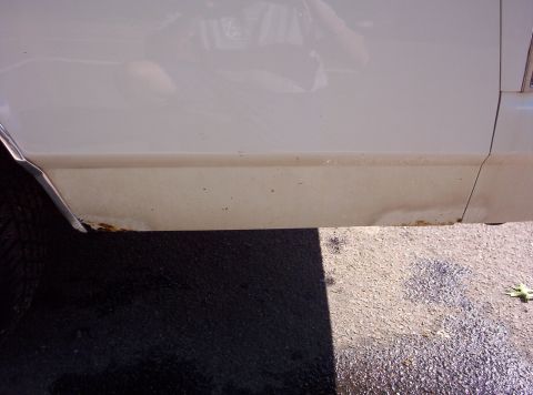 1991 Ford LTD Crown Victoria - This image shows the lower body panel of a white car, highlighting areas of rust and damage.