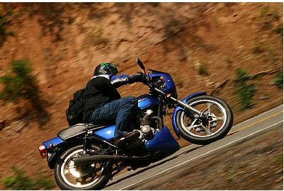 1985 Ford Crown Victoria LTD - Motorcycle rider navigates a curve on a scenic, winding road.