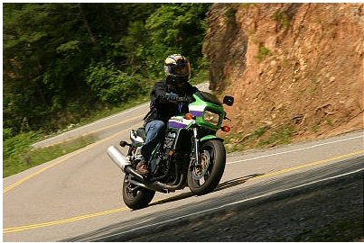 1985 Ford Crown Victoria LTD - A motorcyclist navigates a scenic road, leaning into a turn.