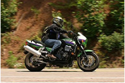 1985 Ford Crown Victoria LTD - A motorcyclist rides a green sportbike down a tree-lined road.