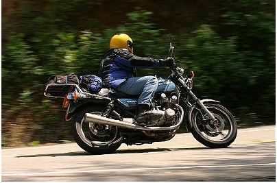 1985 Ford Crown Victoria LTD - A motorcycle rider cruises down a tree-lined road.