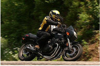 1985 Ford Crown Victoria LTD - Motorcycle rider on a road with trees blurred by motion.