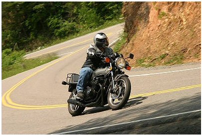 1985 Ford Crown Victoria LTD - A motorcycle navigates a sharp curve on a scenic mountain road.