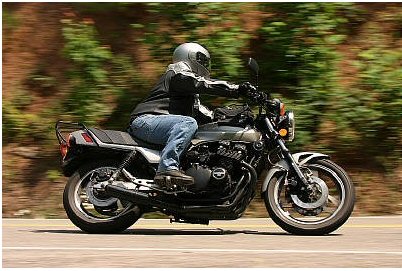 1985 Ford Crown Victoria LTD - Motorcyclist riding on a road with motion blur.