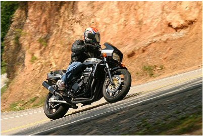 1985 Ford Crown Victoria LTD - A motorcycle rider navigates a curve on a scenic road.