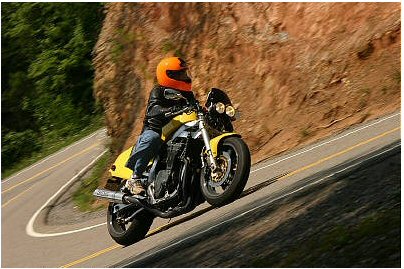 1985 Ford Crown Victoria LTD - A rider on a yellow motorcycle navigates a sharp curve on a scenic mountain road.