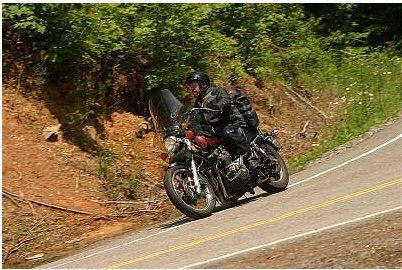 1985 Ford LTD Crown Victoria - A rider navigates a curve on a scenic road, leaning into the turn.