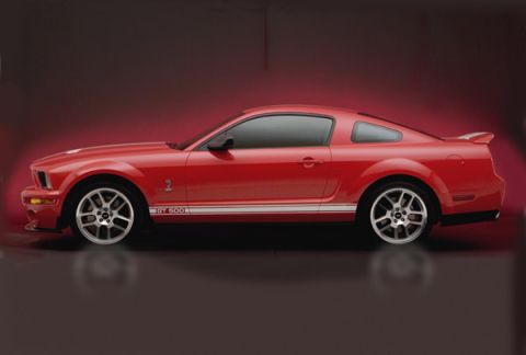 1990 Ford Bronco - Side view of a red Ford Mustang GT500, identifiable by its body style and GT 500 badging.