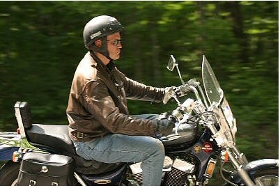 1985 Ford LTD Crown Victoria - Rider on a motorcycle with a windshield and saddlebags on a wooded road.