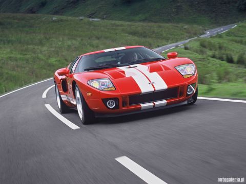 1990 Ford Bronco - A red Ford GT with white racing stripes navigates a curve on a scenic road.