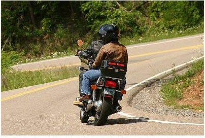 1985 Ford LTD Crown Victoria - Two riders on a motorcycle navigate a scenic, winding road.