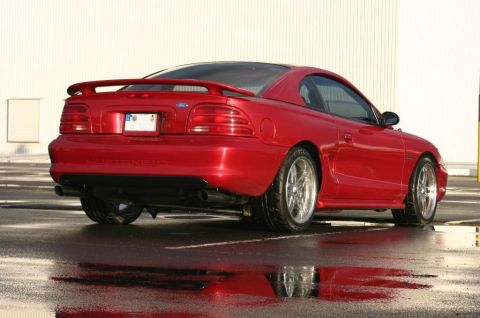 1990 Ford Bronco - Rear view of a red 1994 Ford Mustang coupe with a spoiler and custom wheels.