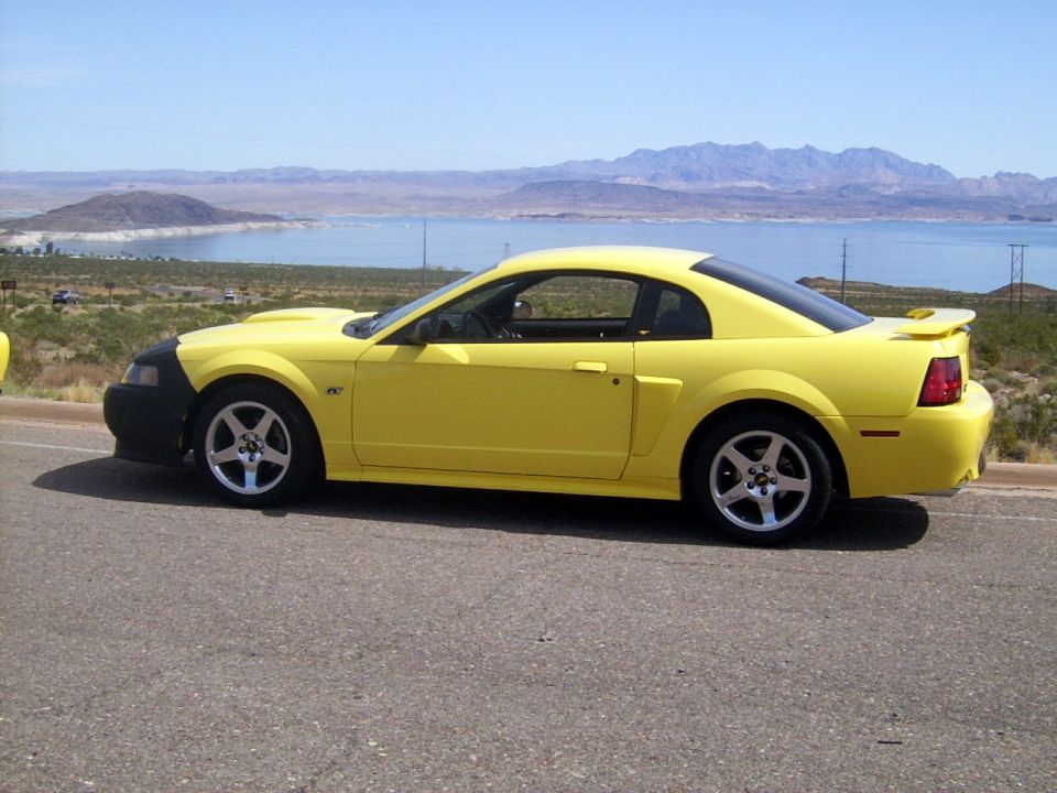 Yellow 2002 Ford Mustang parked roadside with a black front bumper and a spoiler