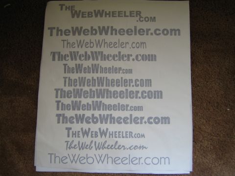1990 Ford Bronco - Photograph of a printed logo and typeface proof sheet for TheWebWheeler.com, not a technical document.