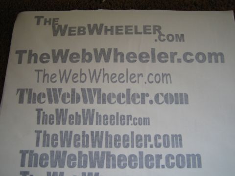 1990 Ford Bronco - Photograph of a printed logo and typeface proof sheet for TheWebWheeler.com, not a technical document.