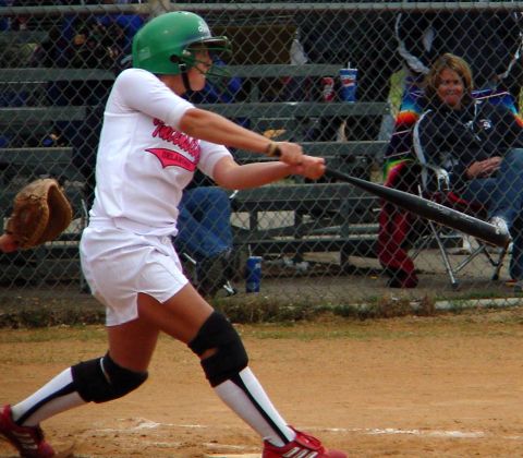 2000 Ford Taurus - A softball player is captured mid-swing during a game, with fans watching from behind a fence.