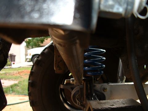 1995 Ford Bronco - This photo shows a close-up view of a vehicle's suspension system, including a blue coil spring and a tire.
