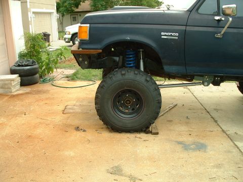 1995 Ford Bronco - A dark blue Ford Bronco with aftermarket suspension and tires is parked in a driveway.