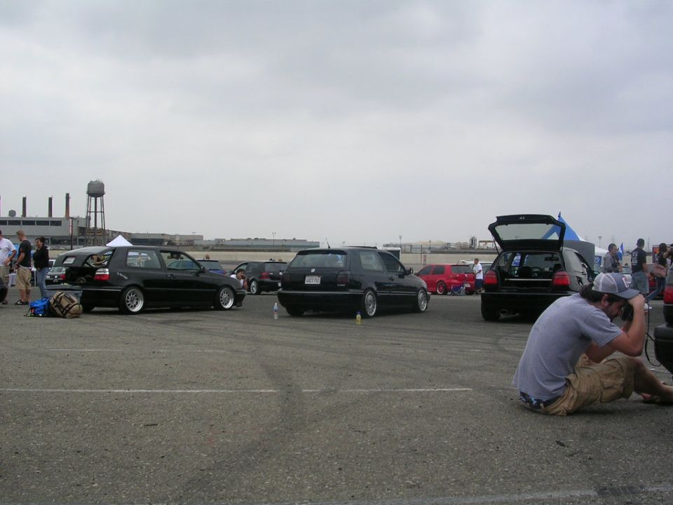 Several black hatchbacks and a red hatchback parked in an outdoor lot