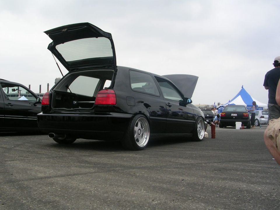 Black hatchback with trunk and hood open, lowered suspension, chrome wheels