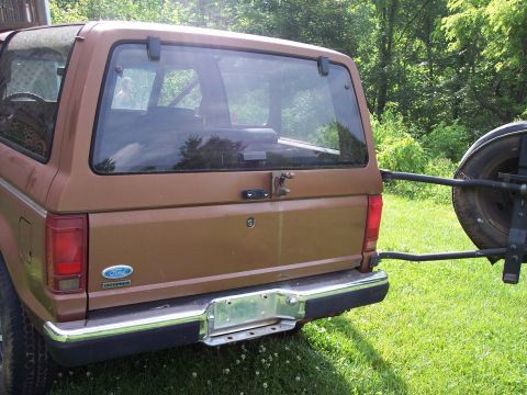1986 Ford Bronco II - The rear of a brown Ford Bronco II is shown with a spare tire mounted externally on a carrier.