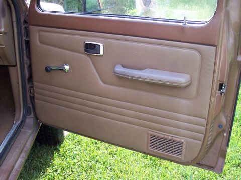 1986 Ford Bronco II - Close-up of the interior door panel of a vehicle, with a window crank and armrest visible.